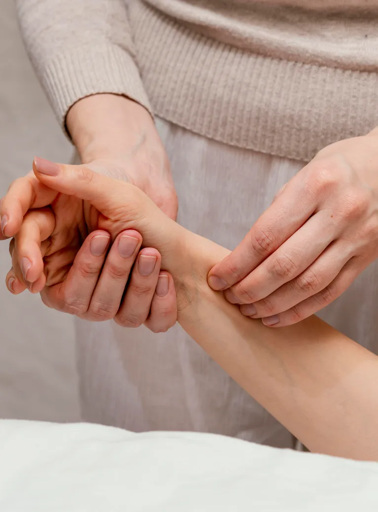 A practitioner working pressure points along a patient's wrist and forearm