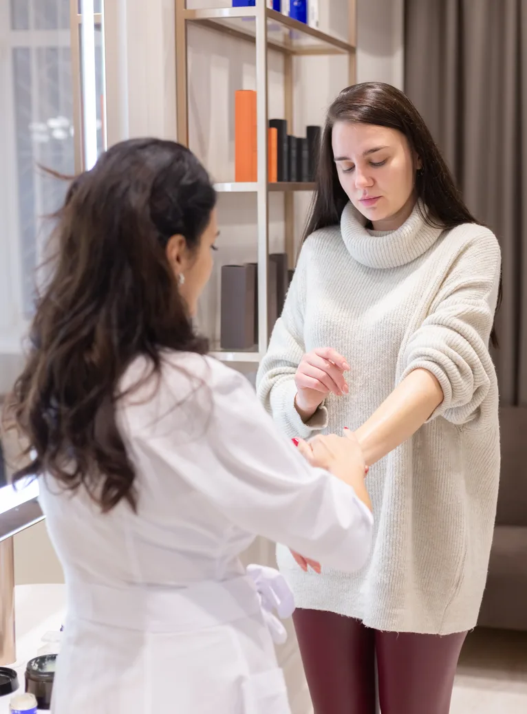 A clinician in a white coat examining a patient's forearm during a consultation