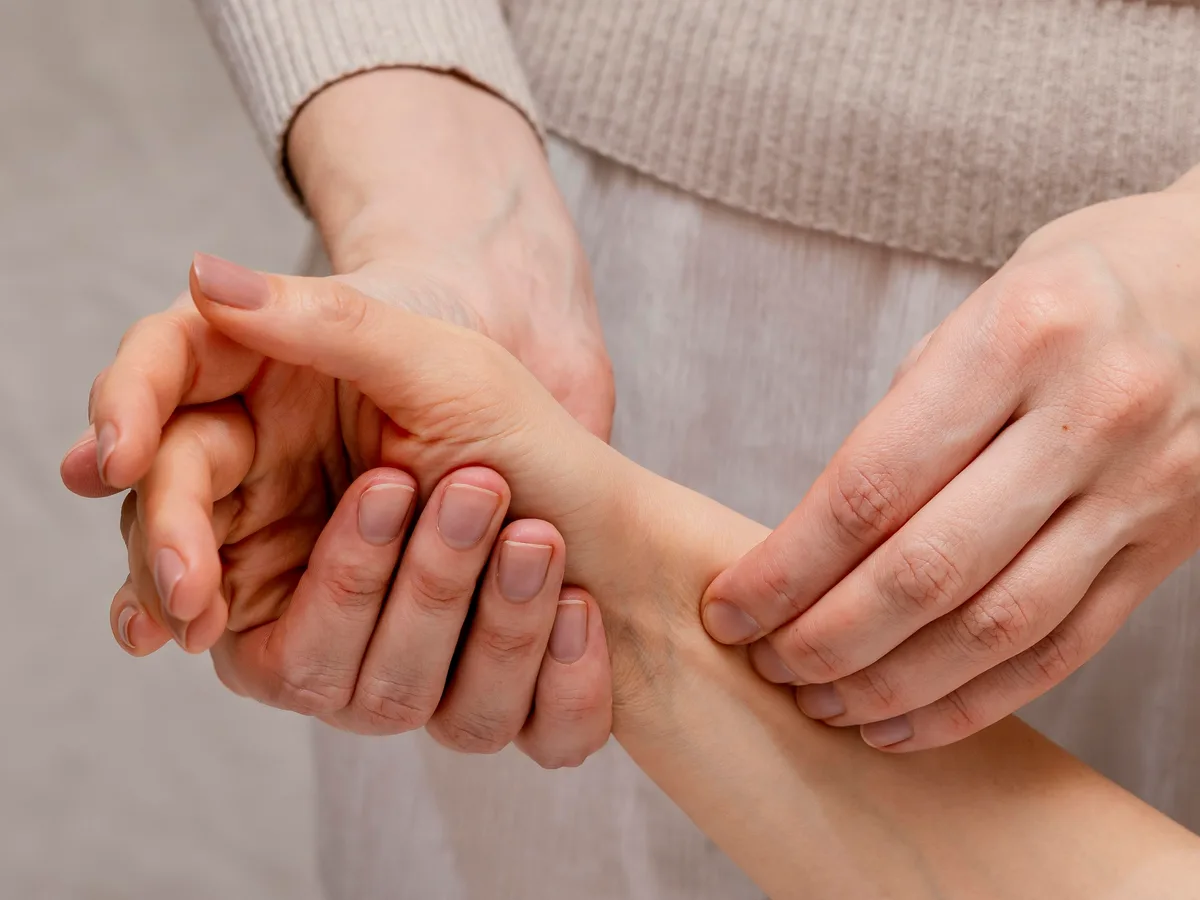 A practitioner working pressure points along a patient's wrist and forearm